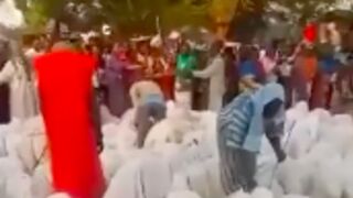 Sex slave market in Africa shows two salesmen surrounded by people covered with white sheets waiting to be purchased