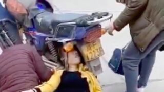 Woman gets her head caught in the arch of a motorcycle