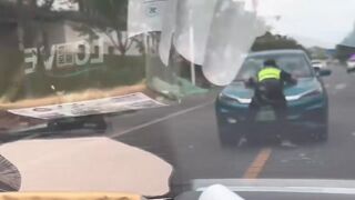 china man driving with officer on his vehicle