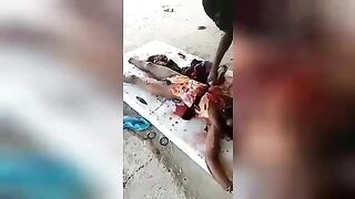 Negroes enthusiastically butcher the corpse of a tribesman