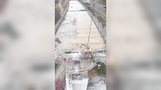 An airborne excavator demolishing a collapsed motorway bridg